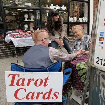 Party Entertainer Elaine, giving Palm and Tarot Reading to a couple in Public on a Spiritual Fair